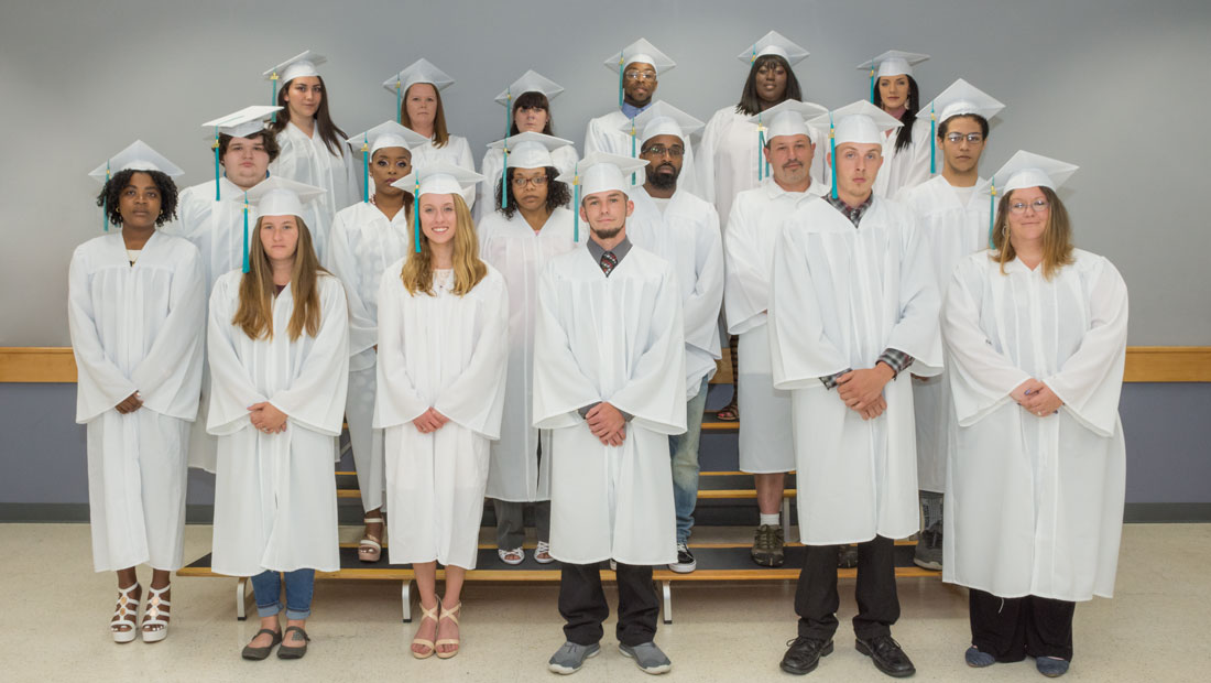 Group of students standing in a white cap and gown
