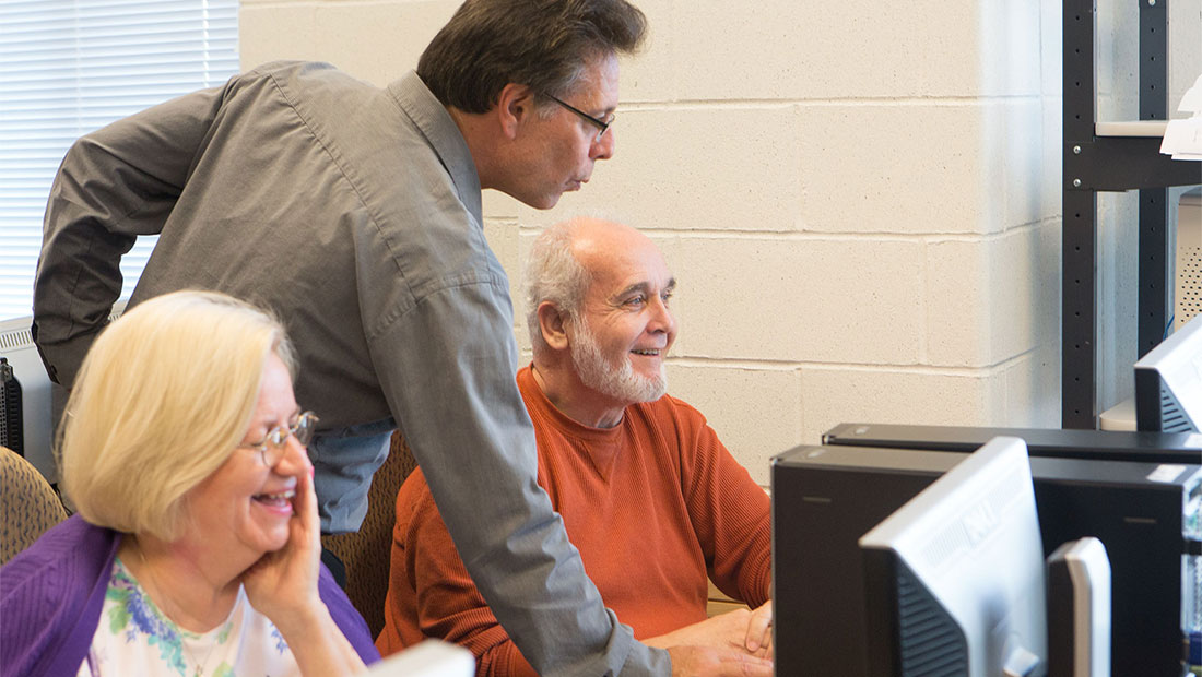 Two seniors looking at a computer with instructor