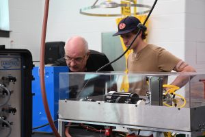 Joe shows a student a piece of equipment in the electromechanical lab