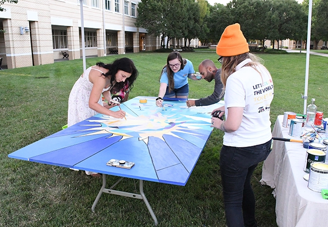 people working on a mural panel